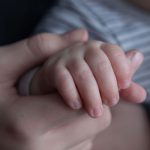 close up of adult hand holding a baby hand