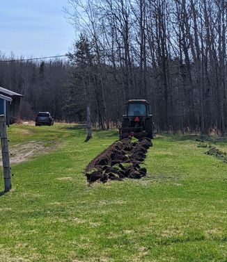 tractor pulling plow through grass and digging it up to make a garden