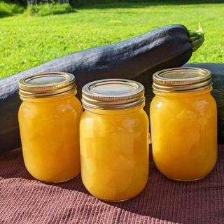 Jars of zucchini pineapple with zucchini in the background