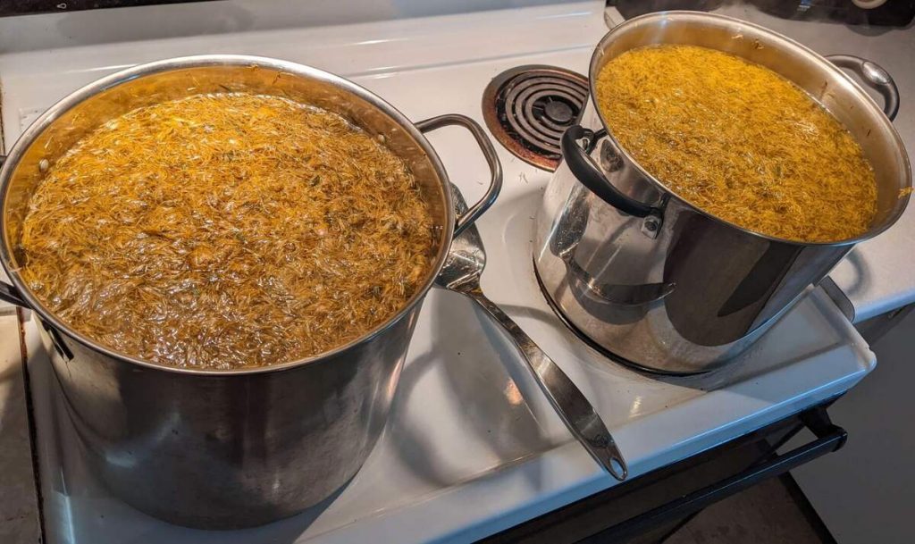 Two stockpots on the stove with dandelion petals steeping inside.