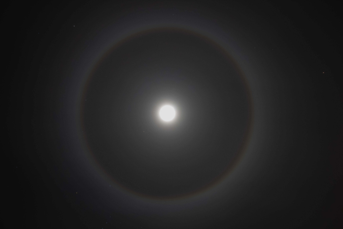 Full moon in the night sky with a large halo surrounding it